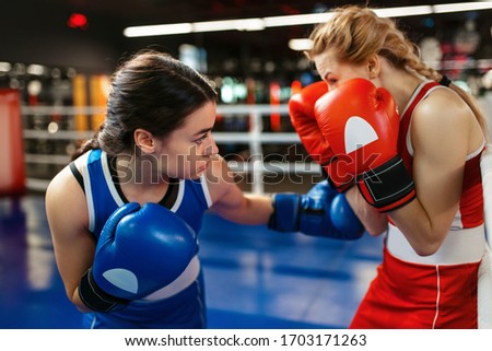 Women in red and blue gloves boxing on the ring