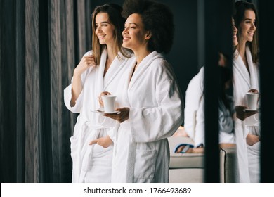 Women relaxing and drinking tea in robes during wellness weekend