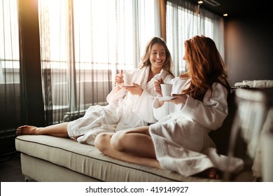 Women relaxing and drinking tea in robes during wellness weekend - Powered by Shutterstock