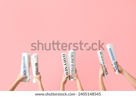 Women with rolled newspapers on pink background
