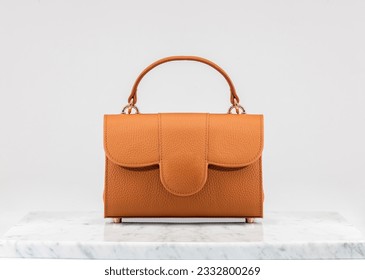 Women 's bag. Luxury, orange leather handbag on white background, on marble floor. A elegant bag is see from front side. Fashionable trendy.