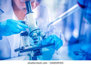 Women scientist looking through microscope in laboratory. Young scientist doing some research with dropper chemical double exposure.