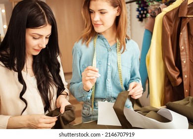 Women Seamstresses Sweep Away, Sew Fabric, Details Of Future Clothes. Happy, Smiling. Fashionable Sewing Studio Indoors. Authentic