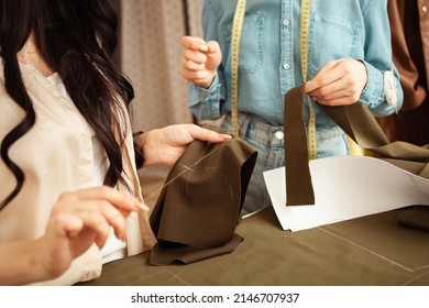 Women Seamstresses Sweep Away, Sew Fabric, Details Of Future Clothes. Fashionable Sewing Studio Indoors.