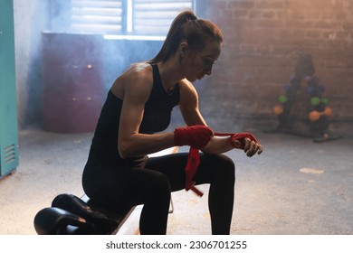 Women self defense girl power. Woman fighter preparing for fight wrapping hands with red boxing wraps sports protective bandages. Strong girl ready for fight active exercise sparring workout training
