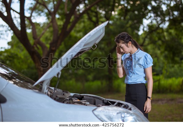 Women She\
opened the hood Broken car on the side See engines that are damaged\
or not.\
Women Broken car in\
Forest