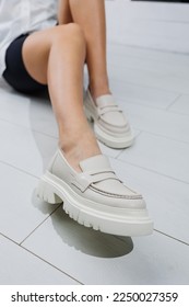 Women shoes. Close up of female legs in leather white loafers. New spring-summer collection of women's leather shoes