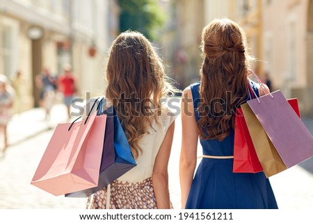 women with shopping bags walking in city