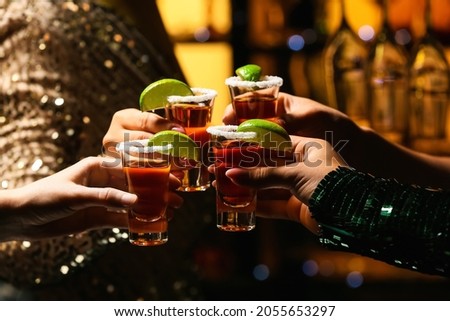 Women with shots of tasty tequila in bar, closeup