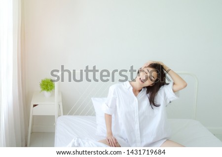 women sit at the edge of the bed. And stretching his arms to relax in the morning.Wake up in the morning. Stretching after waking.Warm tone.Do not focus on the object.