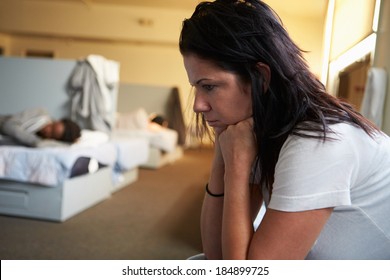 Women Sitting On Beds In Homeless Shelter