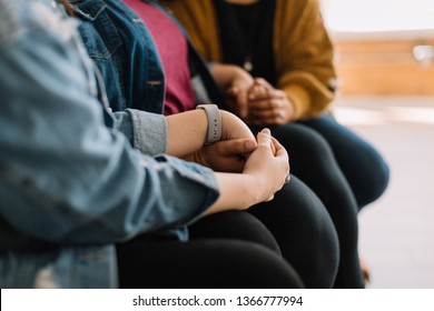 Women sitting on couch holding hands comforting each other.