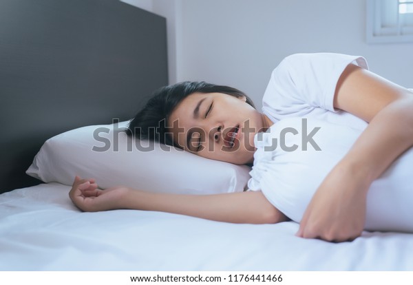 Women sleeping on the bed and grinding teeth,Female tiredness and stress,Sleep bruxism
