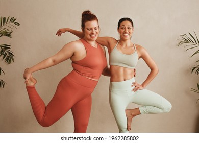 Women sportswear standing together on one leg at fitness studio. Females exercising at health club.