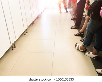 Women standing in row at toilet. Close up queue of women waiting at toilet.