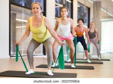 Women Stretching With Resistance Bands On Mats In Fitness Room