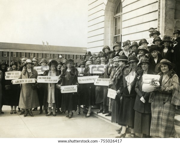 Women Suffragettes holding placards with political\
activist slogans in 1920. Signs read: Know Your Courts-Study Our\
Politicians; Liberty in Law; Law Makers Must Not Be Law Breakers;\
Character in Candi