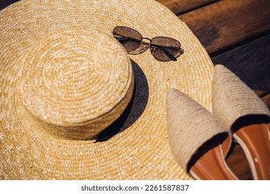 Women summer hat, sunglasses and mules shoes lie on a wooden background. Place for an inscription or advertisement
