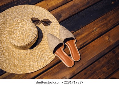 Women summer hat, sunglasses and mules shoes lie on a wooden background. Place for an inscription or advertisement - Powered by Shutterstock