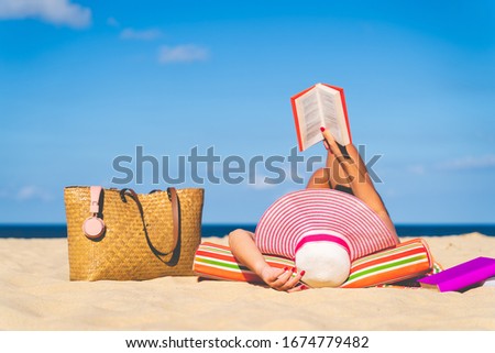 Women are sunbathing and read book on the beach there are bags and books on the side During the holidays in good weather and clear skies during summer, holidays and activities concept with copy space