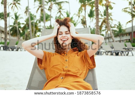    women in a sundress lies in a hammock outdoors on the beach near the trees                            