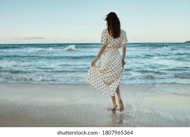 Women In A Sundress On The Sand On The Beach Near The Ocean