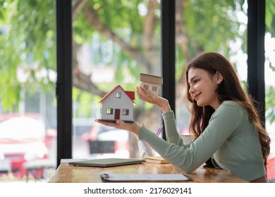 Women support model houses with two hands and give the house over to customers or homebuyers. Rent and buy home or Real Estate Buying Ideas and Investment Banking Finance concept. - Shutterstock ID 2176029141