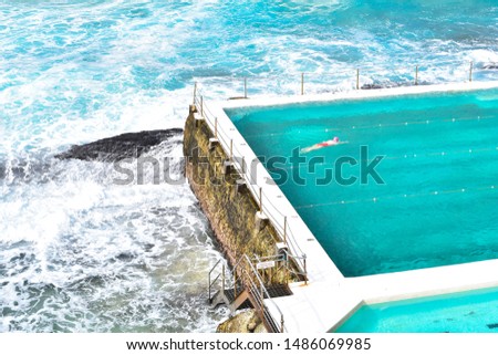 A women swimming in the pool at the Bondi Beach Icebergs Pool, open swimming pool during a day. Bondi beach is one of the most famous tourist sites in Sydney Australia. Deep blue sea and blue water. 