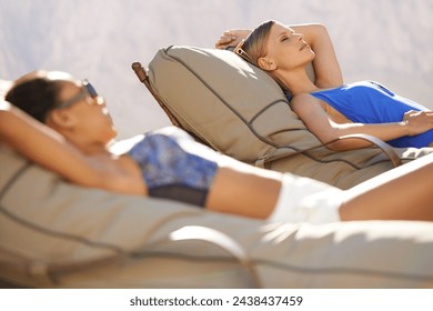 Women, swimwear and lounge chairs for poolside, relax or tanning during summer vacation in Australia. Diverse, female tourists and lying down at holiday resort, wellness spa and luxury hotel - Powered by Shutterstock