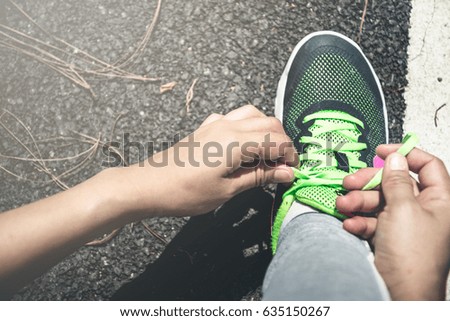 Women tie the chain of jogging shoes. On the runway