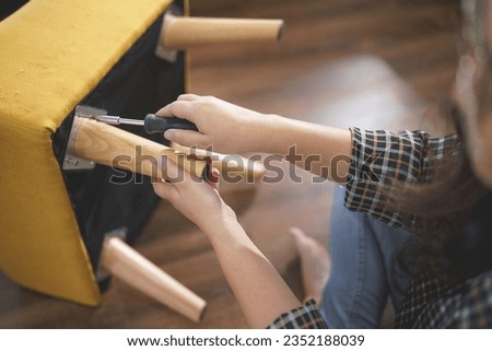 Women tighten screw with screwdriver equipment for assembling leg of chair and making furniture.