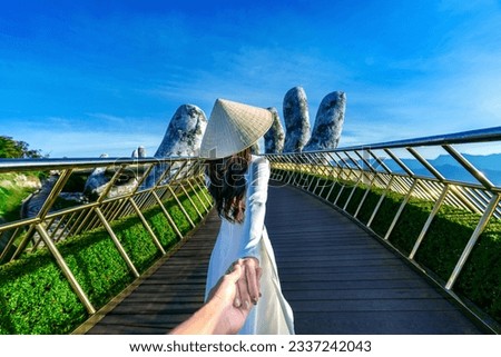 Women tourist holding man's hand and leading him to Golden bridge in Da nang, Vietnam.