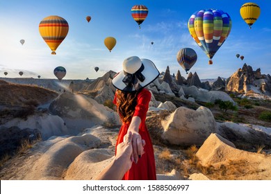 Women tourists holding man's hand and leading him to hot air balloons in Cappadocia, Turkey.