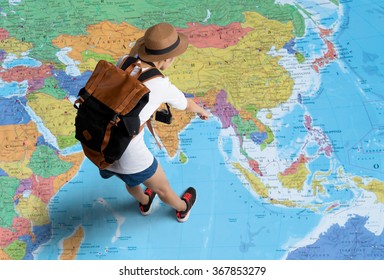 Women traveler Is planning a tour her standing on the world map.She points to the map