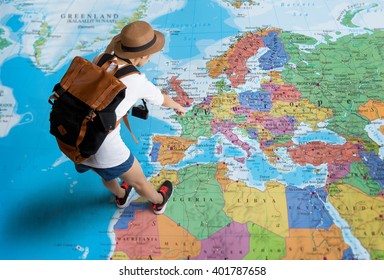 Women traveler Is planning a tour her standing on the world map.she points to the europe
