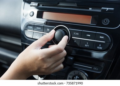 Women Turning Button On Car Radio For Listening To Music