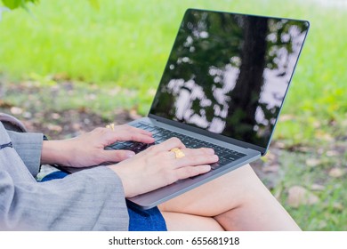 women use laptop on the desk in the park