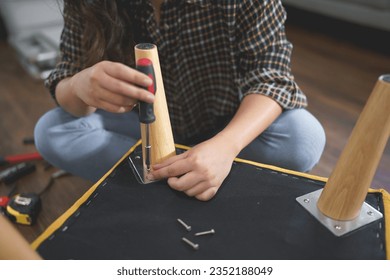 Women use screwdriver equipment to tighten screw while repairing leg of chair and making furniture.