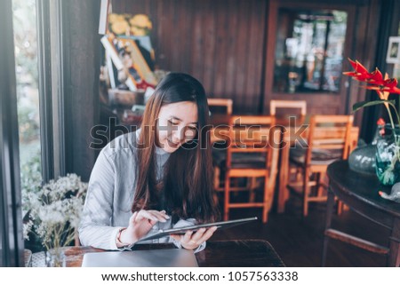 A women using tablet or mobile device on table at garden. She hand taking device and eye see on screen. She sitting in table in the garden and she playing social network.