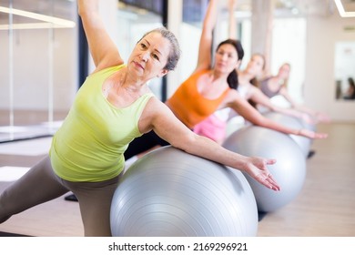 Women of various ages doing stretching exercises with stability balls during group training - Powered by Shutterstock