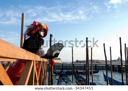 Women in Venetian Carnival costume standing on wooden pier at Grand Canal, Venice.