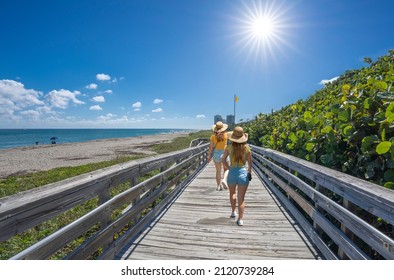 Women Walking On Boardwalk On Beautiful Florida Beach. Girls On Summer Vacation In Florida. Boardwalk Leading To Atlantic Ocean. MacArthur Beach State Park, North Palm Beach, Florida. USA.