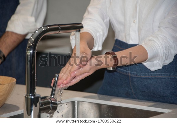 Women wash hands that sync,\
claim to wash hands in the kitchen to prevent germs, causing clean\
hands.