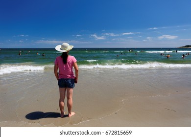 A Women Wearing Beautiful Hat Standing On  Narragansett Town Beach, RI On A Sunny Day. The Beach Is A Classic New England Saltwater Coastal Beach Front.