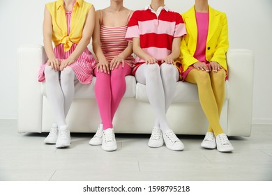 Women wearing colorful tights sitting on sofa indoors, closeup