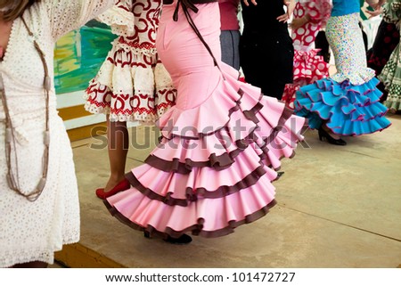 Women wearing flamenco dresses dancing sevillanas at Seville's Feria de Abril.
