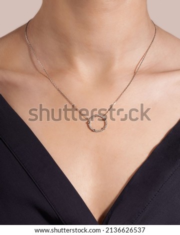 Women wearing jewelry pendant necklace with diamonds on close-up. 