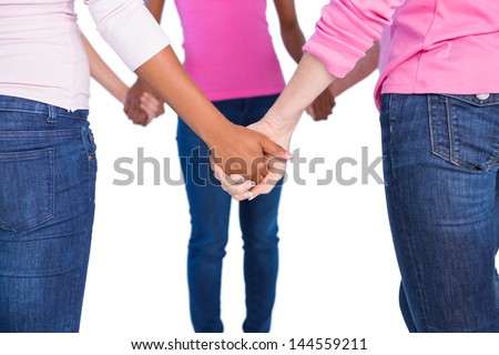 Women wearing pink for breast cancer holding hands on white background