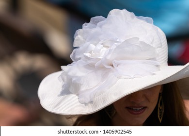 A Women Wearing A White Lace Decretive Hat At A Horse Race.