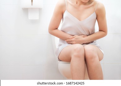 Women wearing white sleepwear, Sit on the toilet 
Stomach ache, excrete, selective focus